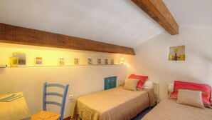 A small, cozy room with two beds, a chair, a table, and a shelf with pictures. - Le 16402 - SARTENE - Gîte (SARTENE)