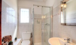 A bathroom with a glass-enclosed shower, a toilet, a sink, and a window providing natural light. - LE GENEVRIER - SERRA DI FERRO (SERRA DI FERRO)