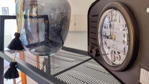 Una radio d'epoca con quadrante circolare e una bottiglia trasparente con manico in corda e nappina.