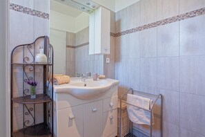 Een badkamer met een wastafel, spiegel en handdoekhouder.