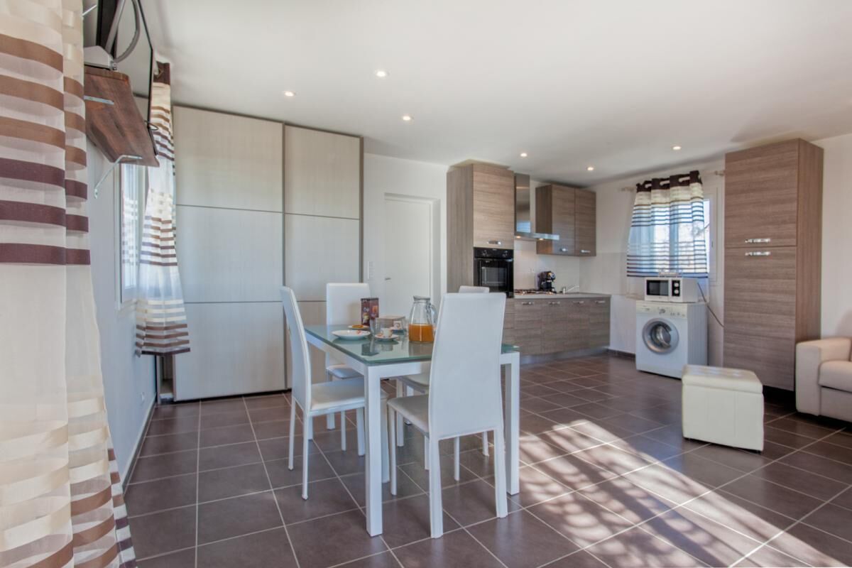 A modern kitchen with a dining area, a washing machine, and a sofa.