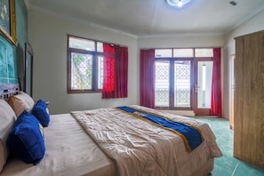 A bedroom with a bed, two windows with curtains, a door, and a wardrobe. - Villa Tjokro 1 By ARBA (Cisarua)