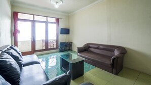 Una sala de estar con sofá, una mesita de centro de vidrio, televisor y un balcón con vistas.