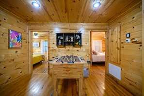 Ein Zimmer mit Holzboden, einer Fußballstoßmaschine, einer Dekorecke und einem Bett im Hintergrund.