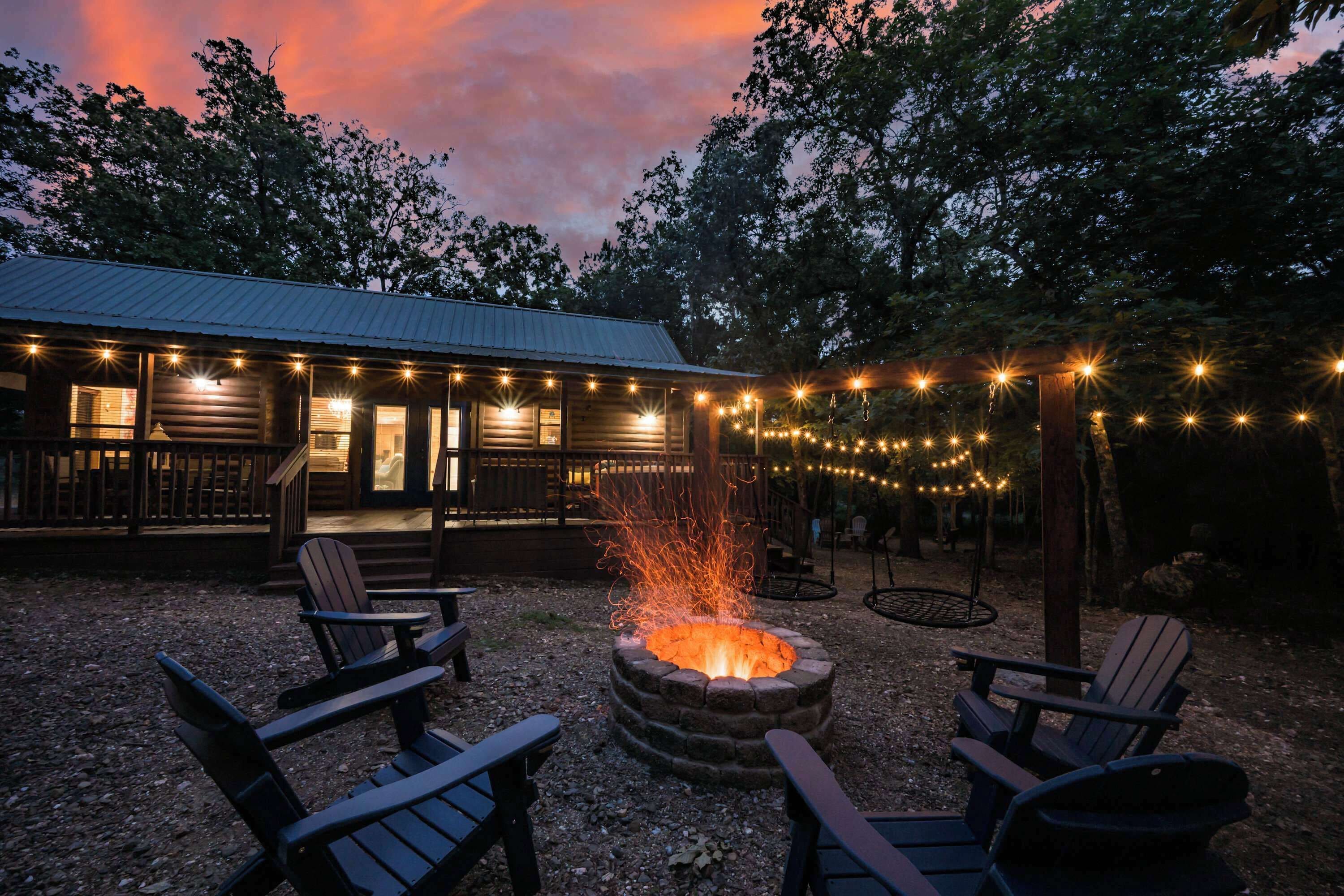 Une cabane en bois avec un foyer, des sièges d’extérieur et des guirlandes lumineuses.