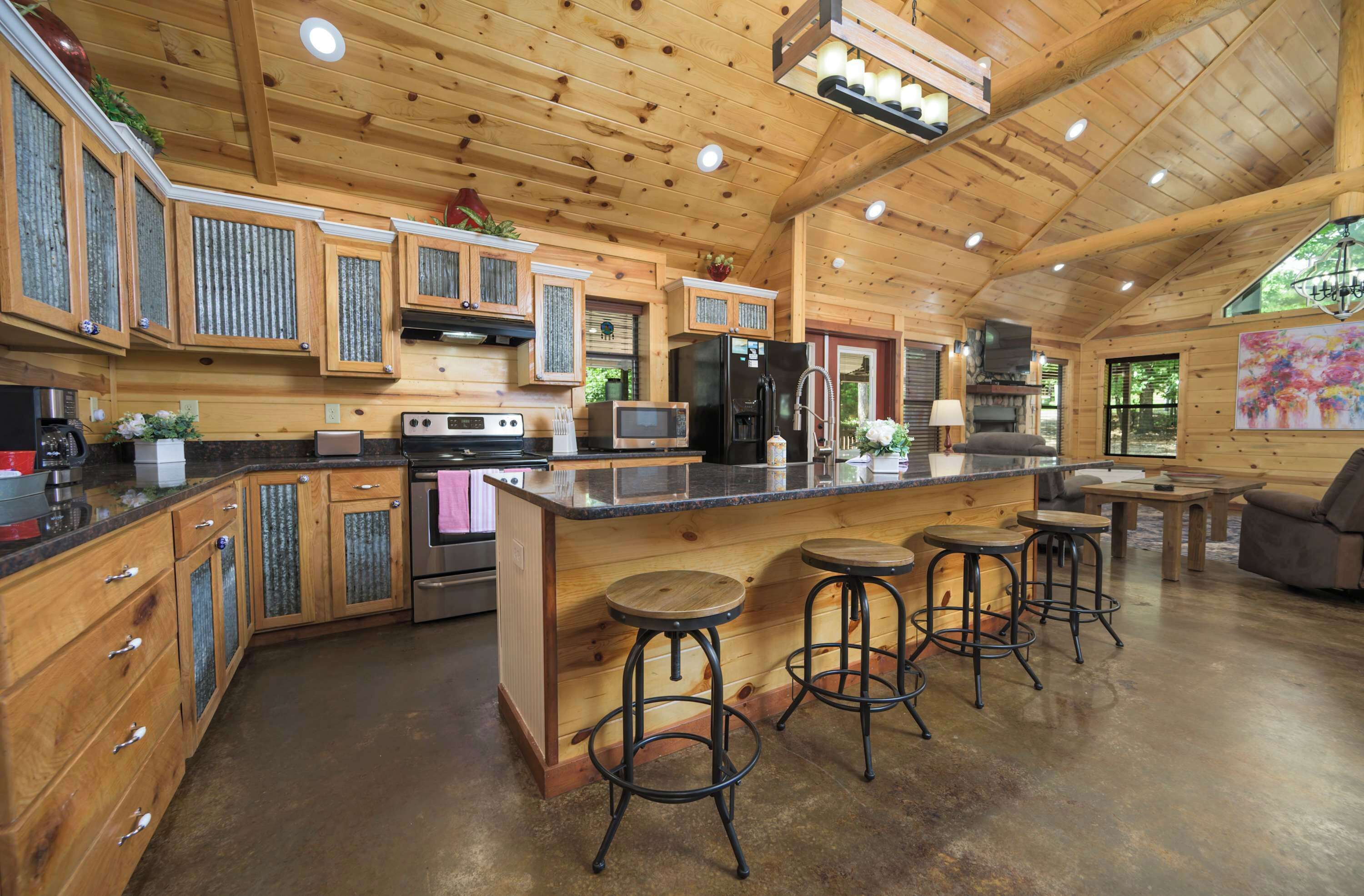 Une cuisine spacieuse avec des meubles en bois, un îlot central doté de tabourets, un réfrigérateur et un four à micro-ondes.