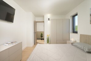 A modern bedroom with a bed, a TV, a wardrobe, and a bedside table with a lamp. - Villa 4M (Istria - Pula) (Pula)