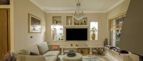 A living room with a sofa, ottoman, TV, and decorative items.