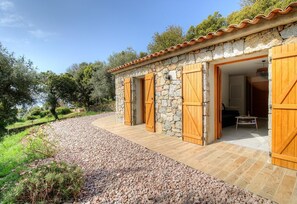 A stone building with wooden doors and a tiled patio. - Les Bergeries de Paomia (CARGESE)