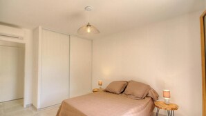 Ett sovrum med en säng, sänglampor, en garderob och en taklampa.