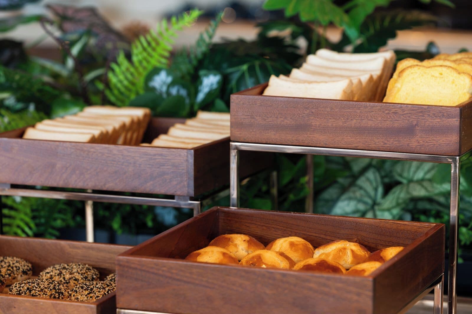 A wooden buffet setup with bread and pastries.