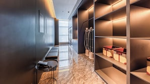 A modern hotel corridor with a marble floor, built-in benches, and shelves with storage bins.