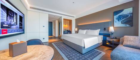 Een moderne hotelkamer met een groot bed, een bureau, een stoel, een televisie en een schilderij aan de muur.