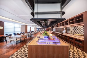 A modern restaurant with a long counter, seating area, and a chef at work.