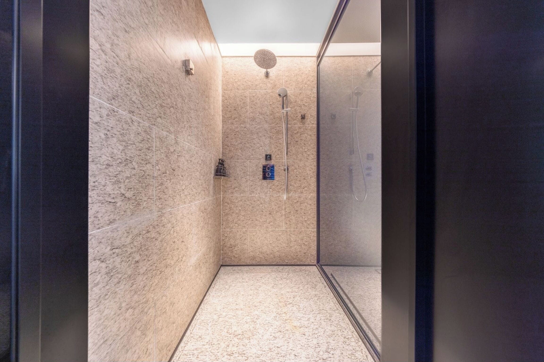 A modern bathroom with a shower, tiled walls, and a glass door.