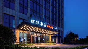 A modern hotel building with illuminated signage, a glass facade, and a well-lit entrance.