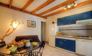 Eine kleine Küche mit blauen Schränken, einem weißen Kühlschrank und einem Essbereich mit einem Tisch für zwei Personen.