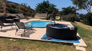 Ein Garten mit Swimmingpool, Liegestühlen, Whirlpool und Rasenfläche.