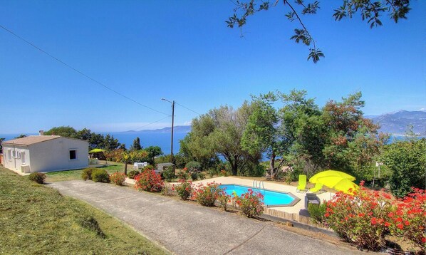 Une propriété résidentielle dotée d’une piscine, d’une petite maison et offrant une vue sur la mer.