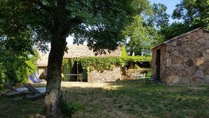 A stone building with a tiled roof, a tree in the foreground, and outdoor seating. - Gîte U Forro - SARI SOLENZARA (SARI SOLENZARA)