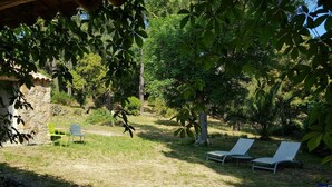 A garden with a stone wall, two lounge chairs, and a small table. - Gîte U Forro - SARI SOLENZARA (SARI SOLENZARA)