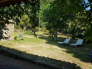 Ein Garten mit einer Steinmauer, zwei Liegestühlen und einem kleinen Tisch.