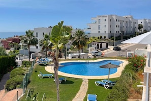 A swimming pool with lounge chairs, palm trees, and a building with 'villa selere' signage. - Stylish Sea-View Retreat in Casares Playa (Casares)