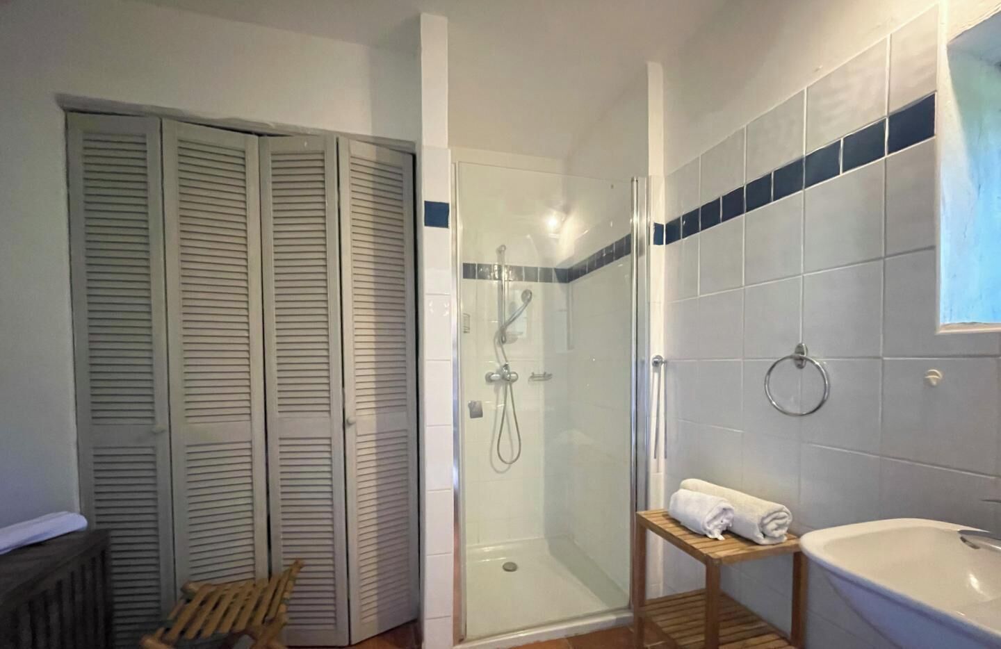 Ein Badezimmer mit Duschkabine, einer Holzbank, einer Badewanne und einem Handtuchhalter.