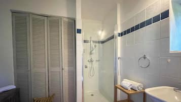 Ein Badezimmer mit Duschkabine, einer Holzbank, einer Badewanne und einem Handtuchhalter.