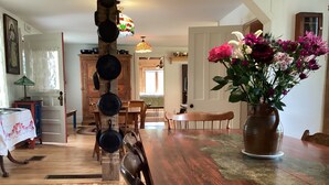 A dining area with a wooden table, chairs, a vase of flowers, and a hanging pot rack.