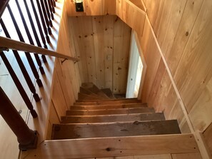 Eine Holztreppe mit Handlauf, die zu einer höheren Etage führt.