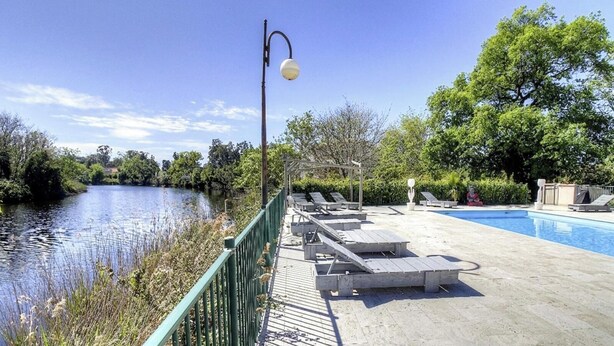 A pool area with lounge chairs, a bridge, and a lamp post. - Résidence U Quarciu - GHISONACCIA (GHISONACCIA)