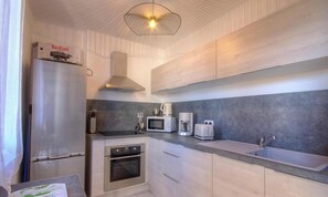 Eine kleine Küche mit Kühlschrank, Backofen, Mikrowelle, Toaster und Spüle.