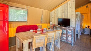 A wooden interior with a dining table, chairs, a red refrigerator, a television, and a small kitchen area. - Résidence U Quarciu - GHISONACCIA (GHISONACCIA)