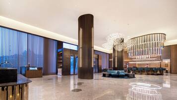 A spacious lobby with a reception desk, seating area, and a large decorative column.