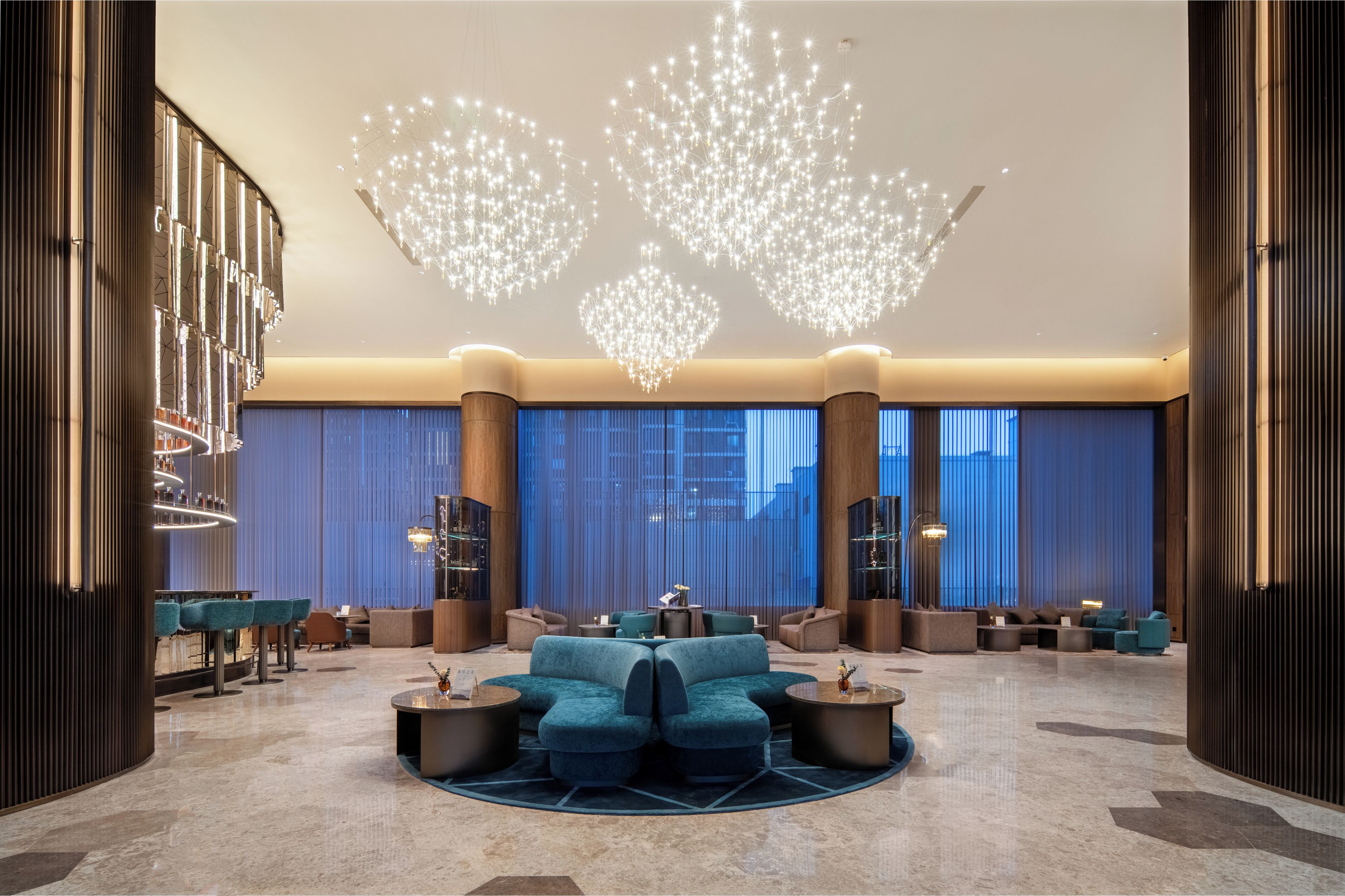 A modern lobby with a central seating area, large windows, and a unique ceiling light fixture.