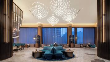 A modern lobby with a central seating area, large windows, and a unique ceiling light fixture.