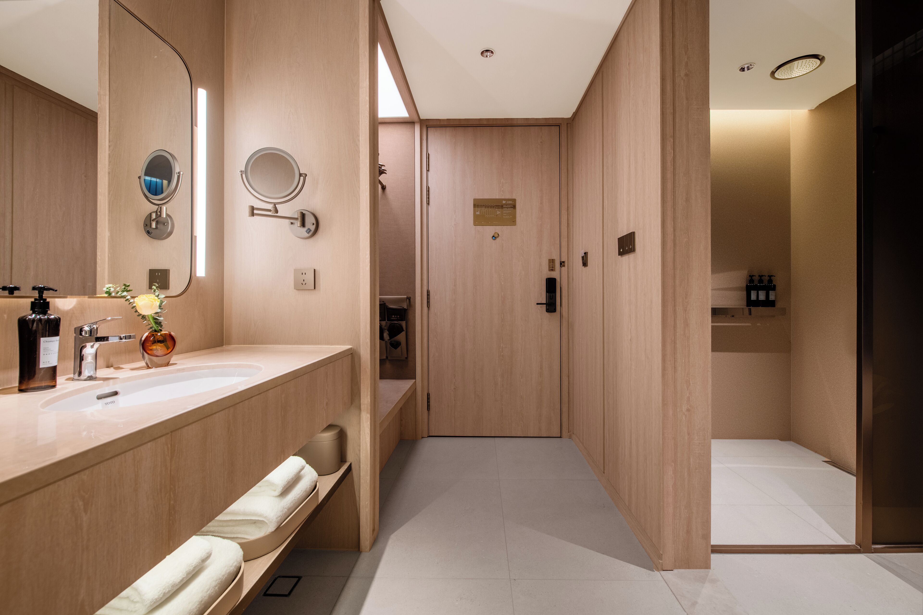 A modern bathroom with a wooden vanity, a large mirror, and a shower area.