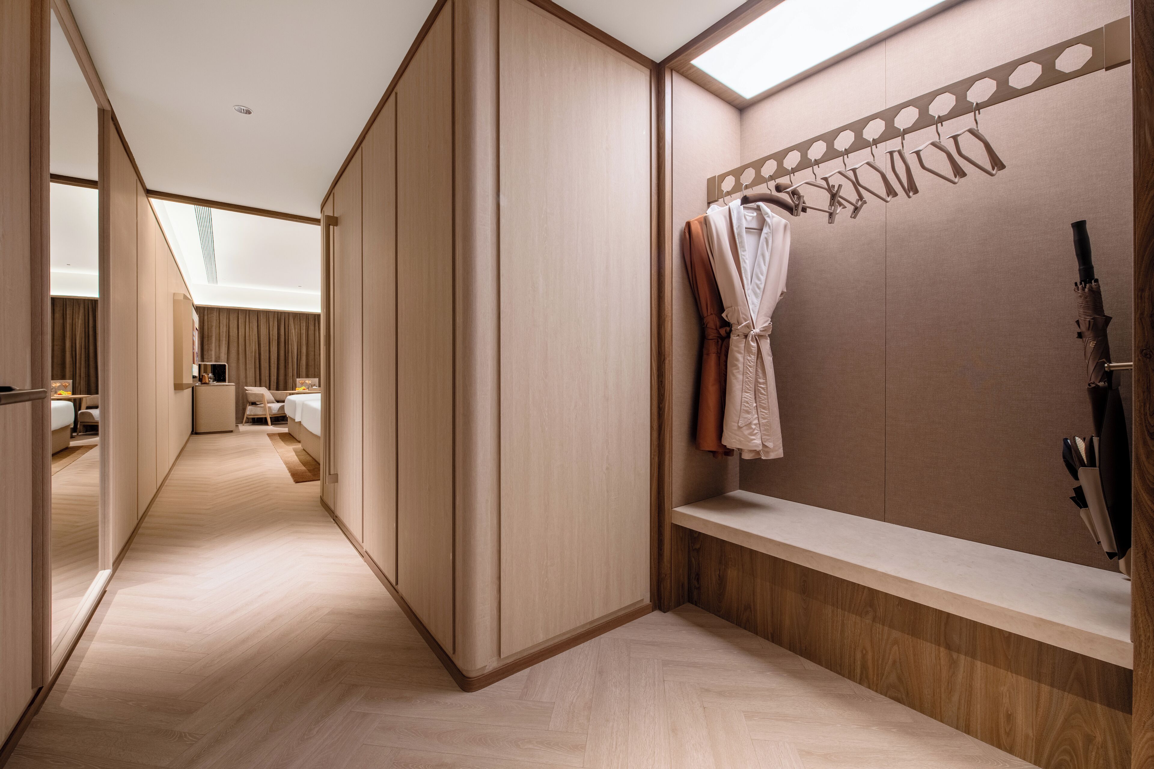 Une chambre d’hôtel moderne dotée d’un dressing, d’une coiffeuse avec miroir et d’un coin salon offrant une vue agréable.