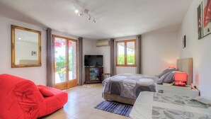 A bedroom with a bed, a television, a red chair, and a window. - Alta Rocca - ALATA - Gîte (ALATA)