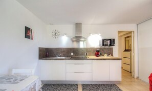 Eine moderne Küche mit weißen Schränken, einer Edelstahl-Dunstabzugshaube, einer Mikrowelle und einem roten Wasserkocher.