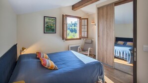 Une chambre à coucher comprenant un lit, une chaise, une fenêtre et une porte donnant sur une autre pièce.
