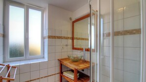Une salle de bain avec une fenêtre, un miroir, un lavabo et une douche.