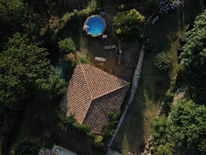 Vista aèria d'una propietat amb piscina, teulada d'aparença daurada i vegetació al voltant.