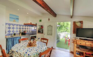A cozy kitchen with a dining area, a TV, and a garden view. - Macadia - AULLENE - Gîte (AULLENE)