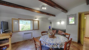 Ein Essbereich mit einem runden Tisch, Stühlen, einem Fernseher, einem Fenster und einer Tür.