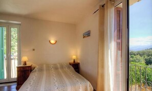 Ein Schlafzimmer mit einem Bett, zwei Nachttischlampen, einer Wandleuchte und einem Balkon mit Blick.