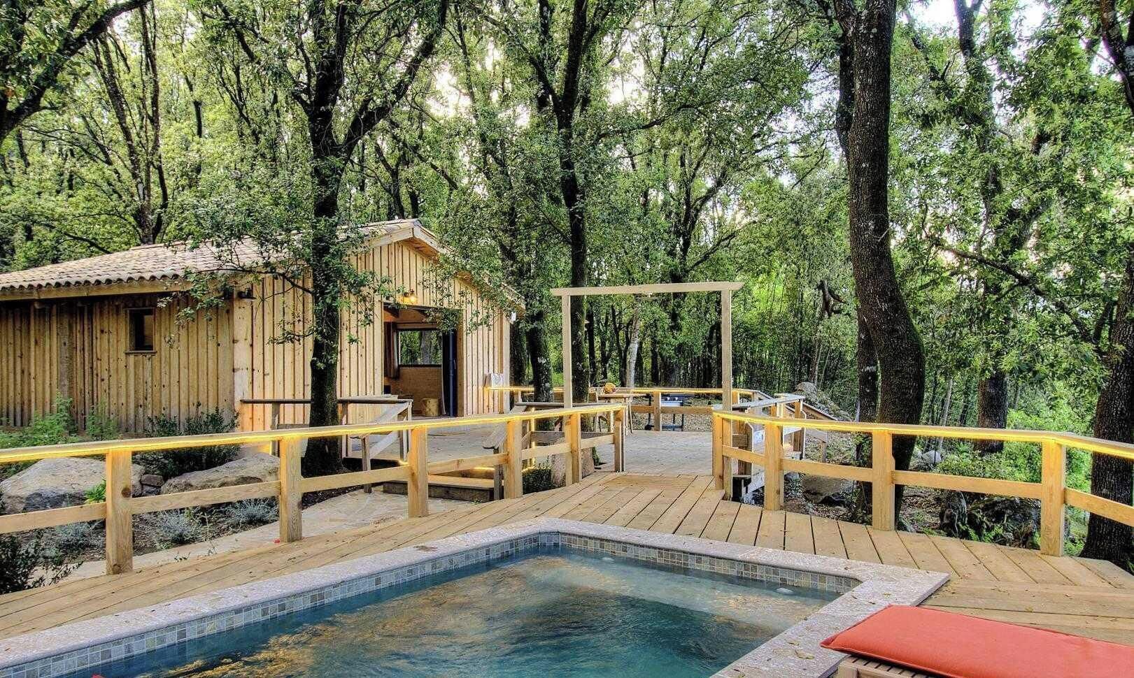 A wooden deck with a pool, surrounded by trees.