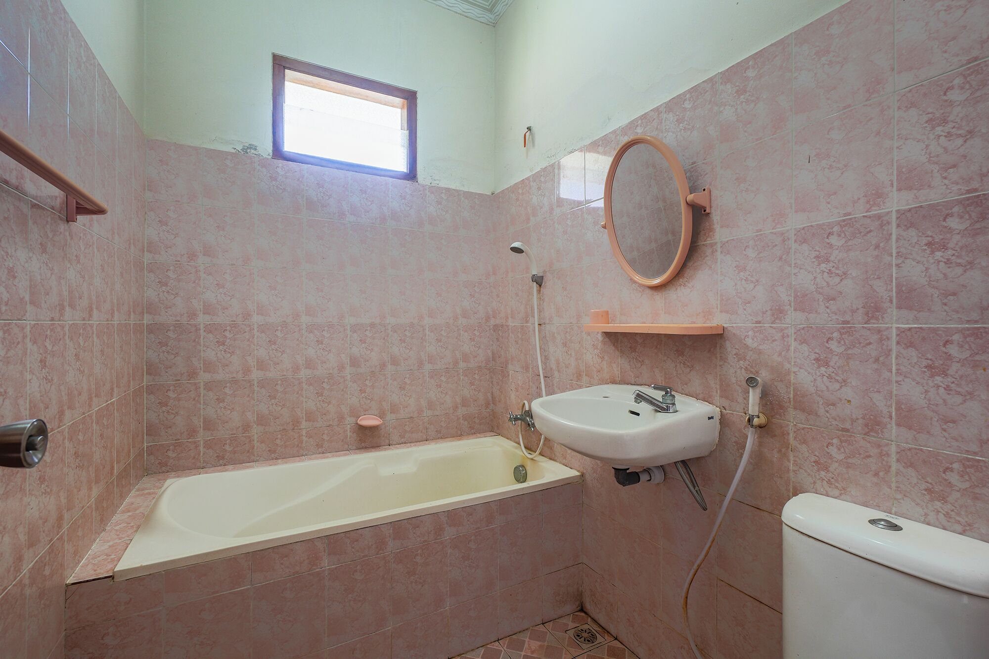 A bathroom with a bathtub, toilet, sink, and a small window.