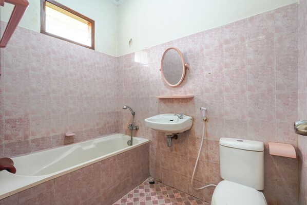A bathroom with a bathtub, sink, toilet, and a mirror. - Villa Tjokro 3 By ARBA (Cisarua)